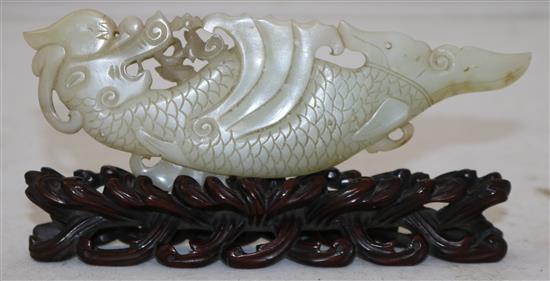 A Chinese pale celadon jade fish-dragon plaque, 18th century, 14cm, with a rosewood stand carved as waves